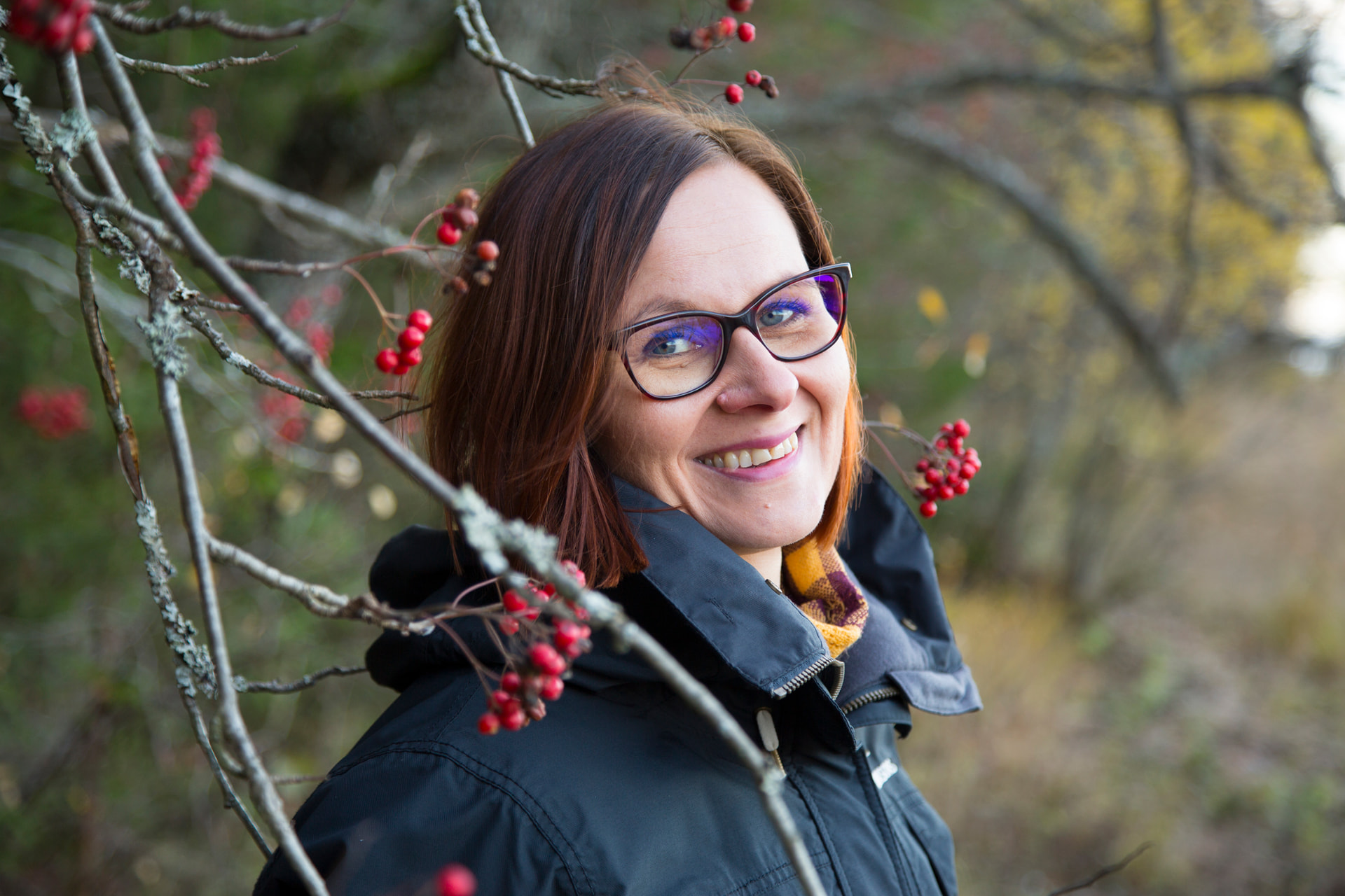 Psykoterapeutti ja työnohjaaja Anna hymyilee syksyisessä pihlajametsässä
